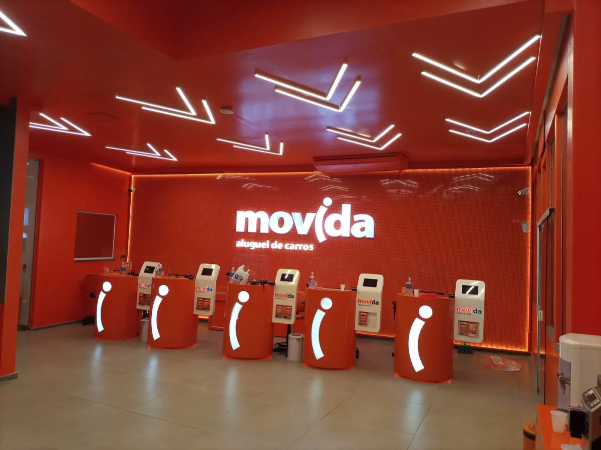 Comunicação visual interna de loja Movida no Rio de Janeiro: letreiro luminoso, painel iluminado e totens de atendimento produzidos pela Do it! Print
